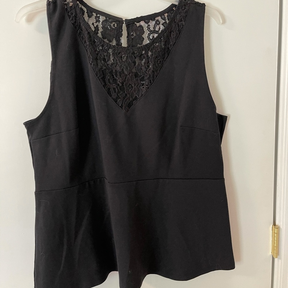 Sleeveless black shirt with peplum hem and lace.